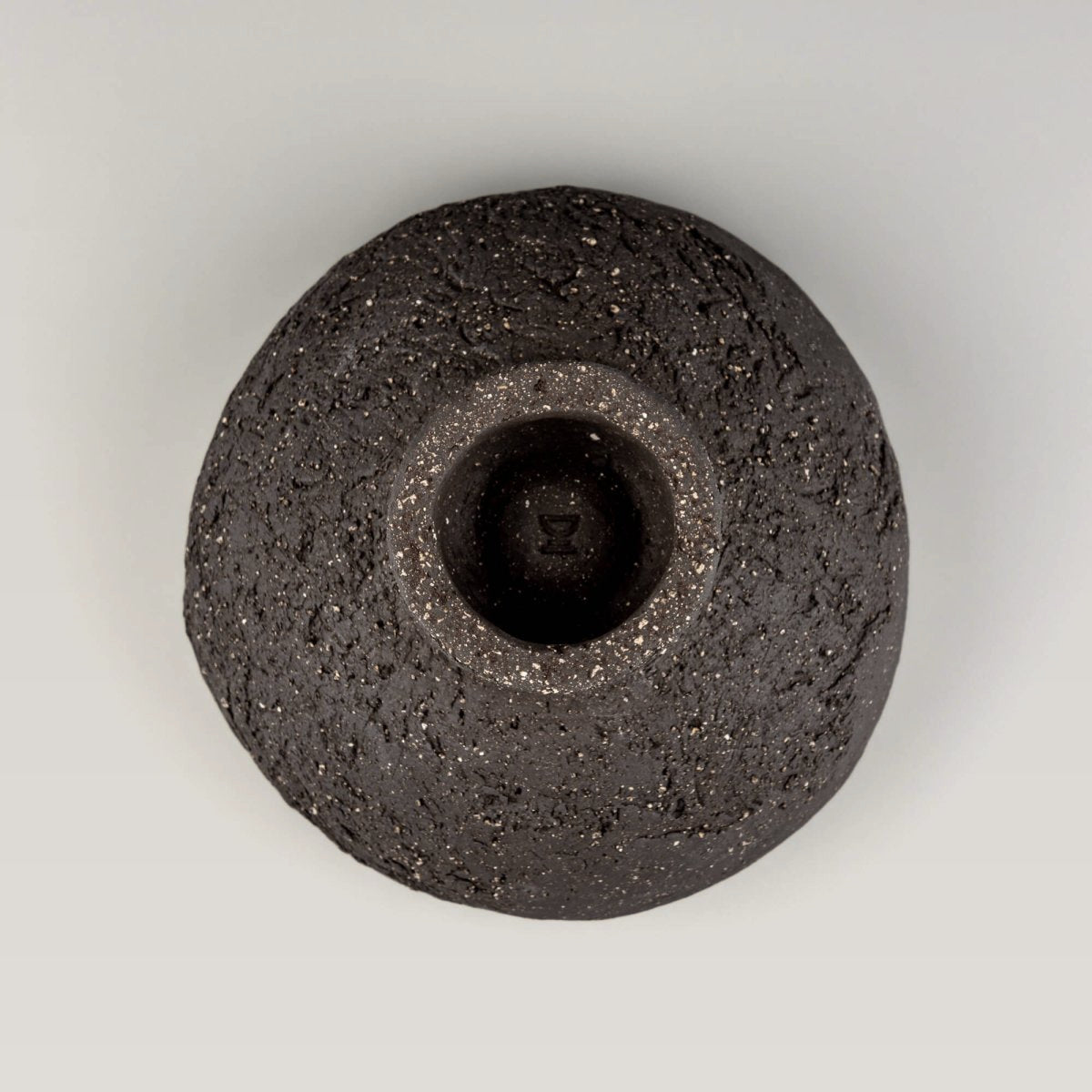 Bottom view of handmade decorative bowl showing raised foot, dark speckled clay, and sculptural handmade construction.