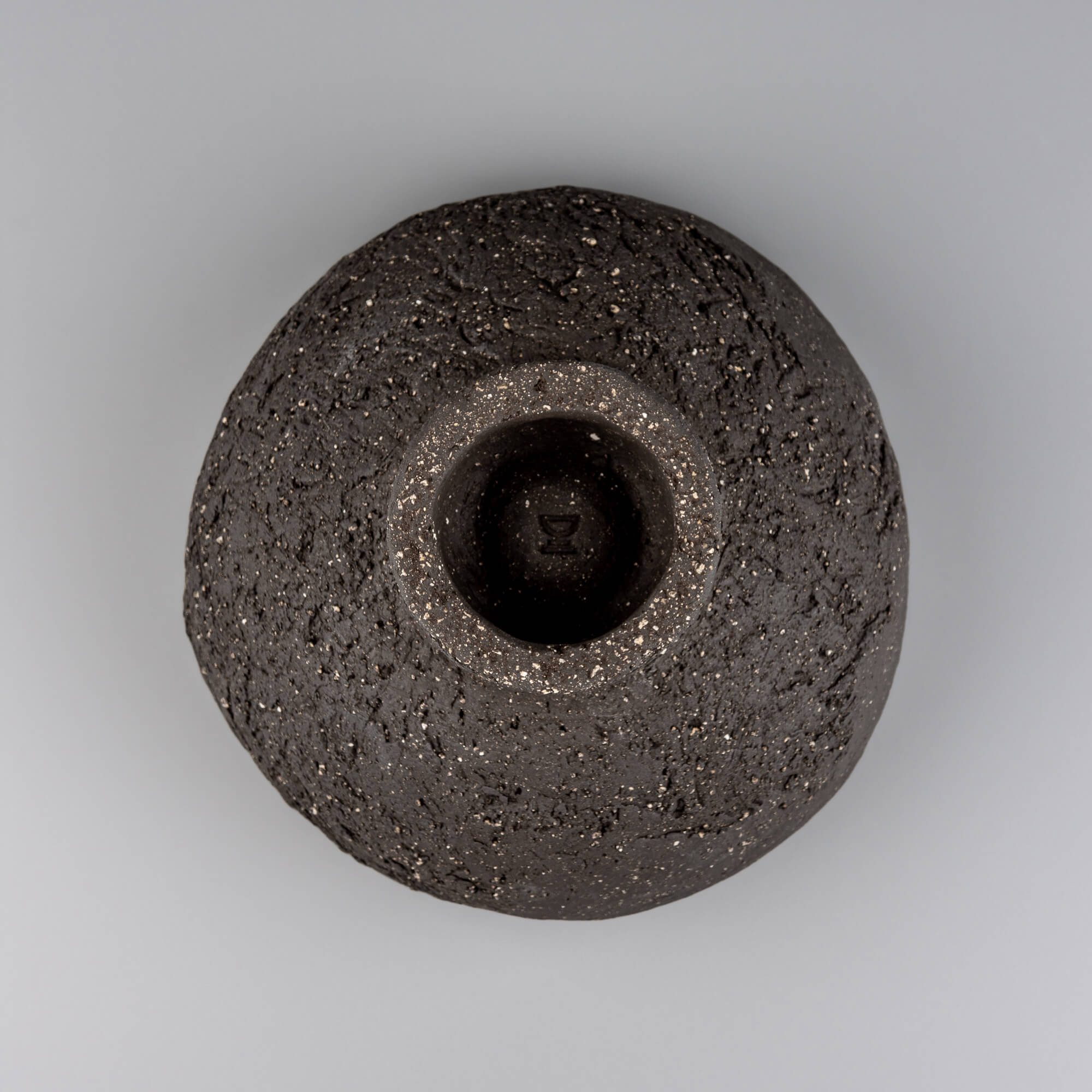 Bottom view of handmade decorative bowl showing raised foot, dark speckled clay, and sculptural handmade construction.