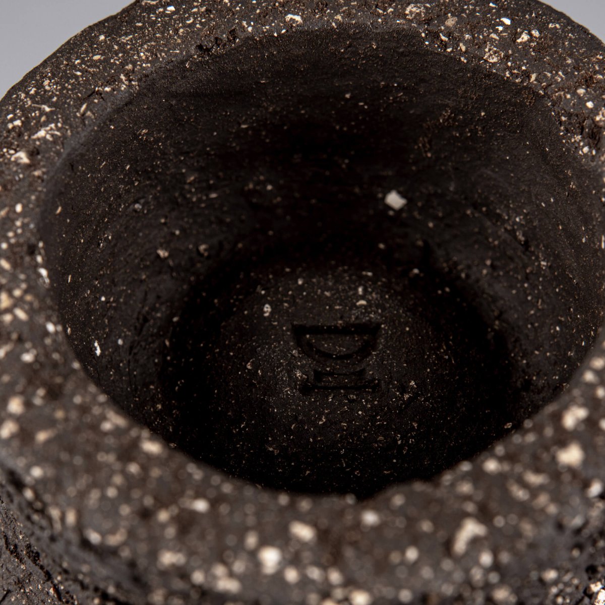 Interior detail of handmade decorative bowl with deep foot ring, raw dark ceramic texture, and artisan pottery finish.