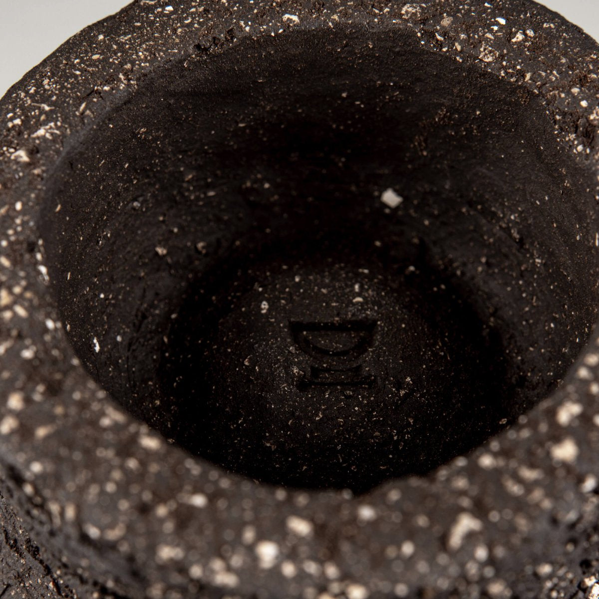 Interior detail of handmade decorative bowl with deep foot ring, raw dark ceramic texture, and artisan pottery finish.