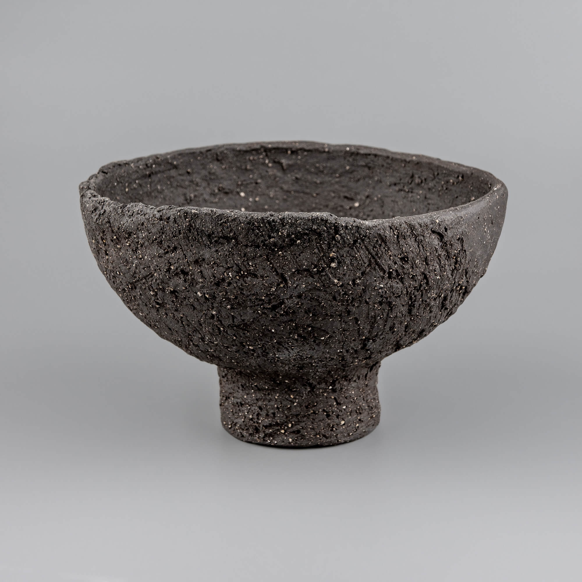 Angled view of handmade decorative bowl showing deep interior, raw rim, and sculptural form for boutique hotel styling.