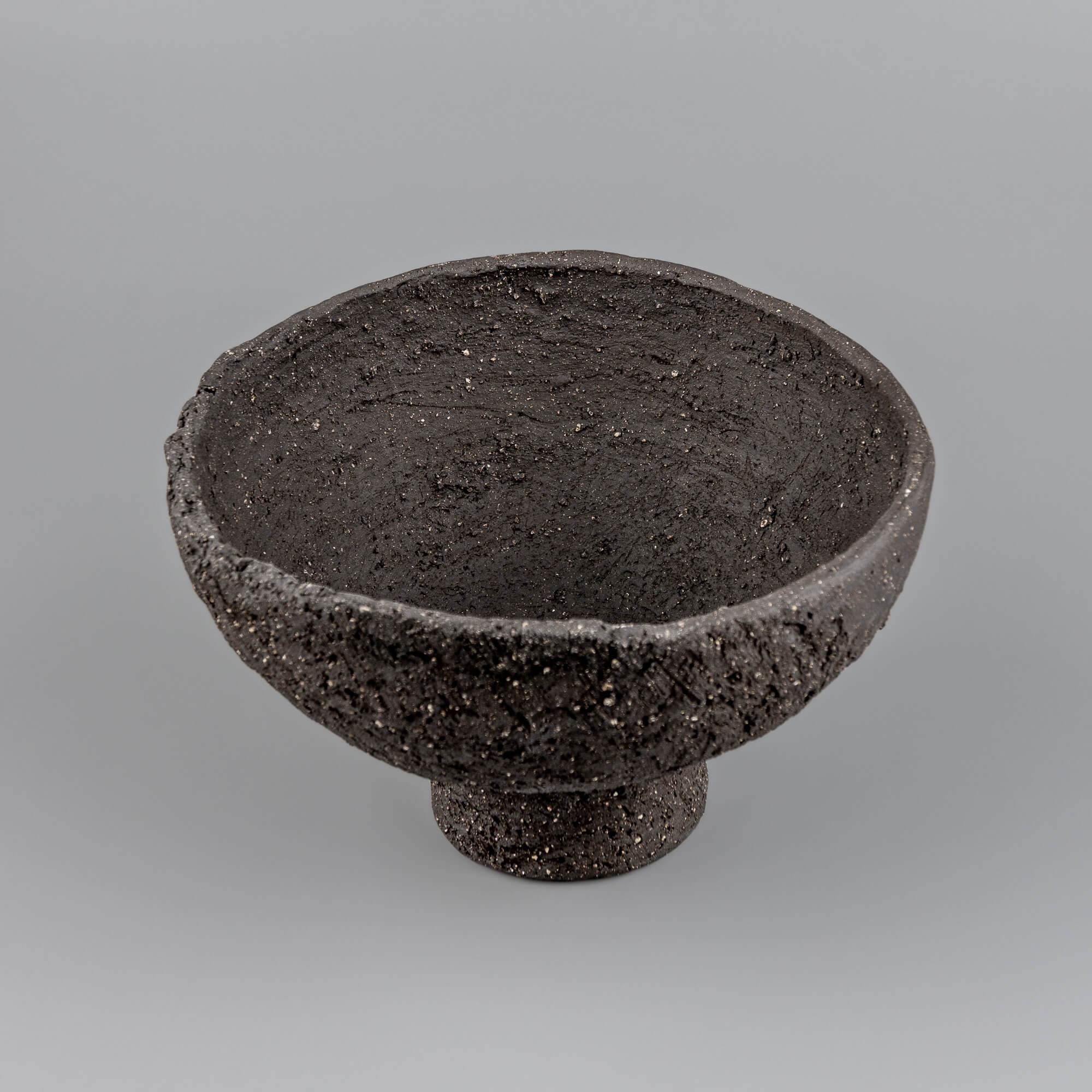 Top view of handmade decorative bowl with dark textured interior, irregular rim, and refined handmade decor character.