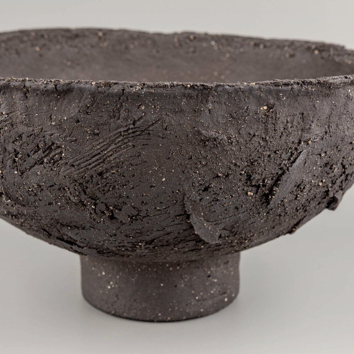 Handmade decorative bowl side detail with raw charcoal clay, raised texture, and sculptural centerpiece presence.