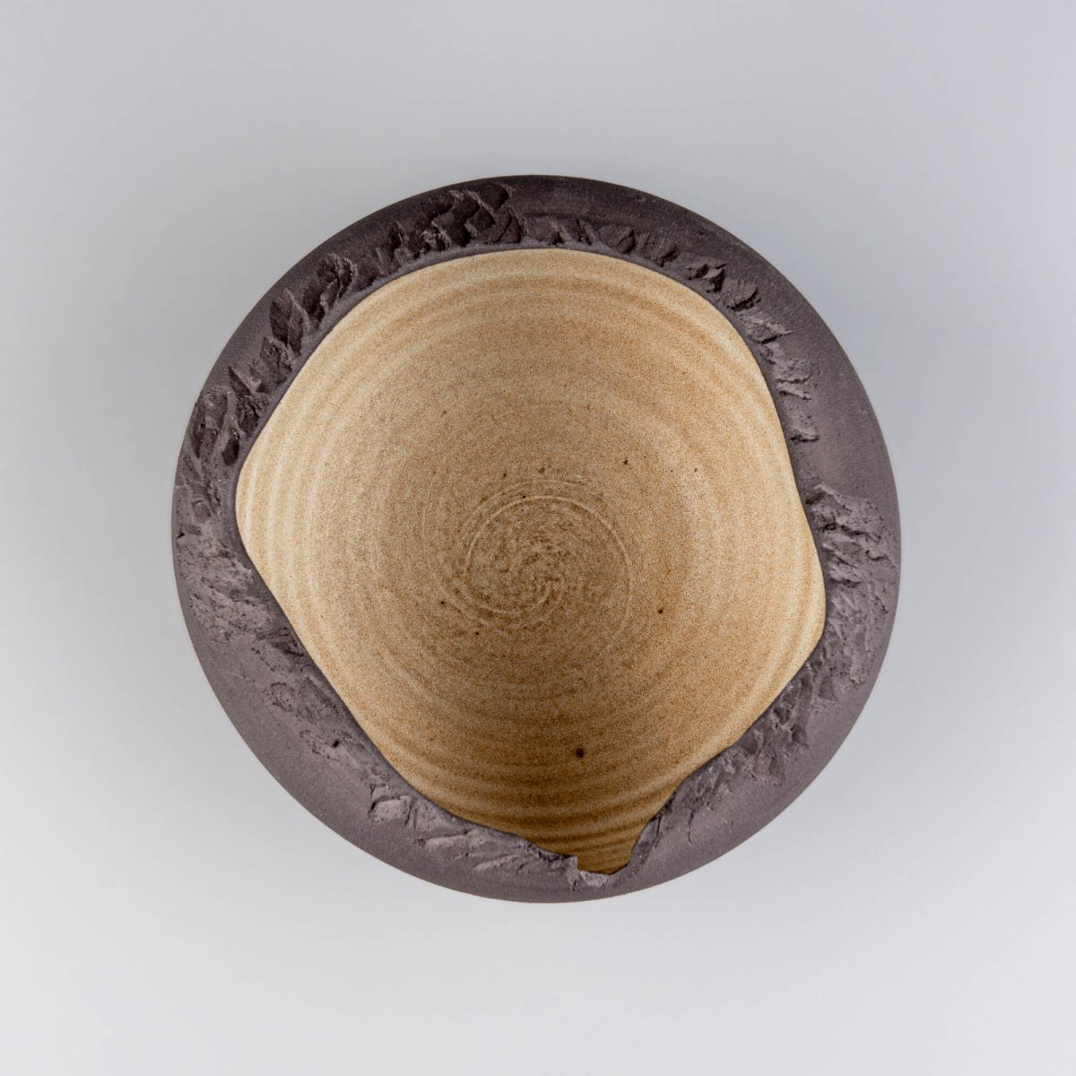 Top view of artisan ceramic bowl showing golden-glazed interior and unglazed matte edges.
