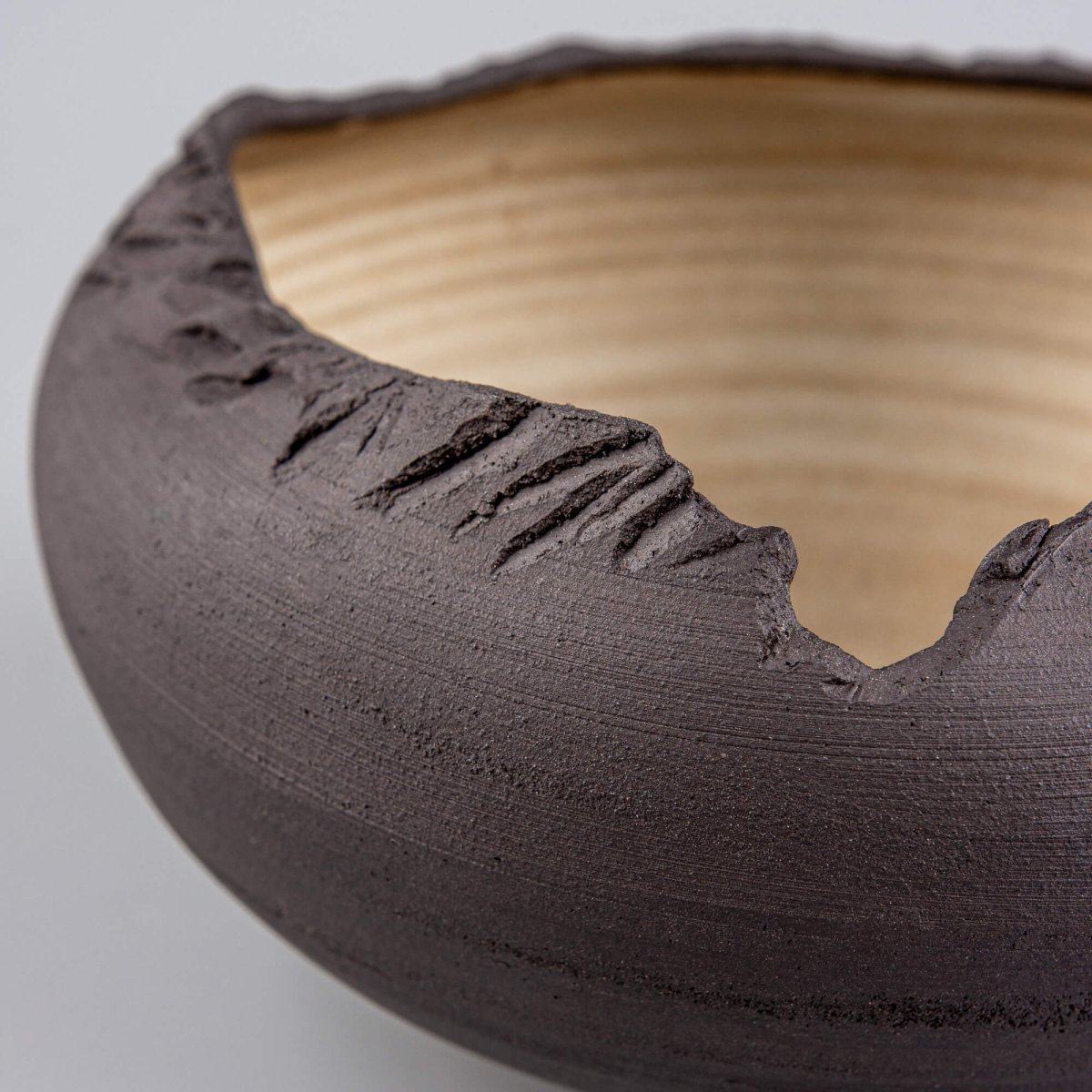 Detail shot of rugged hand-carved rim on matte black ceramic serving bowl.