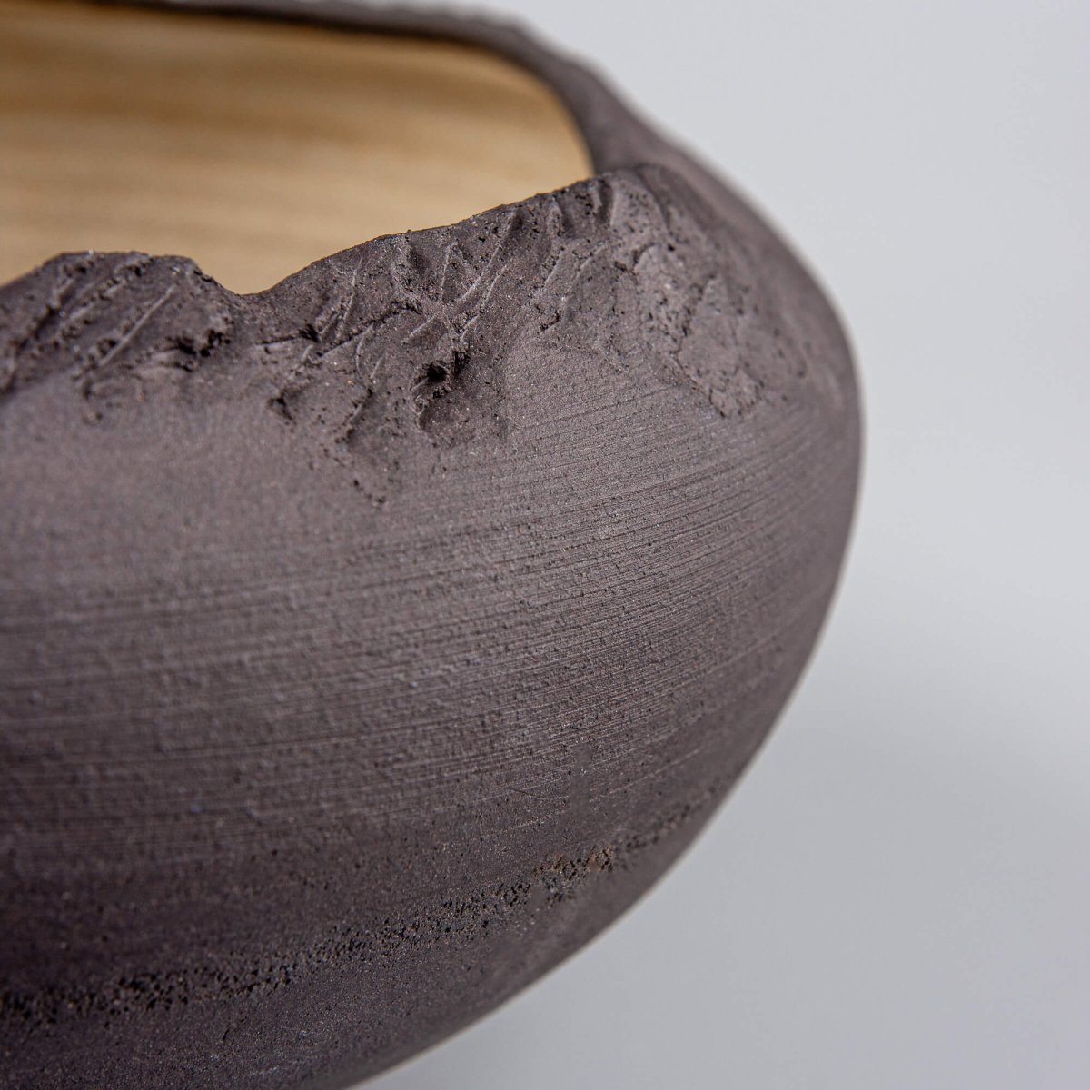 Close-up of contrast between matte black exterior and light golden interior on handmade bowl.