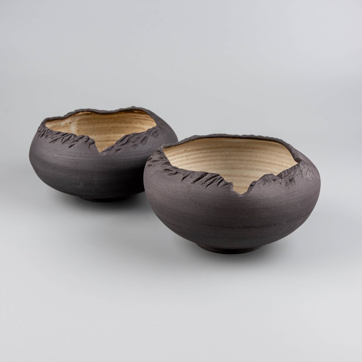 Pair of handmade stoneware bowls displaying variation in glaze and hand-textured surfaces.