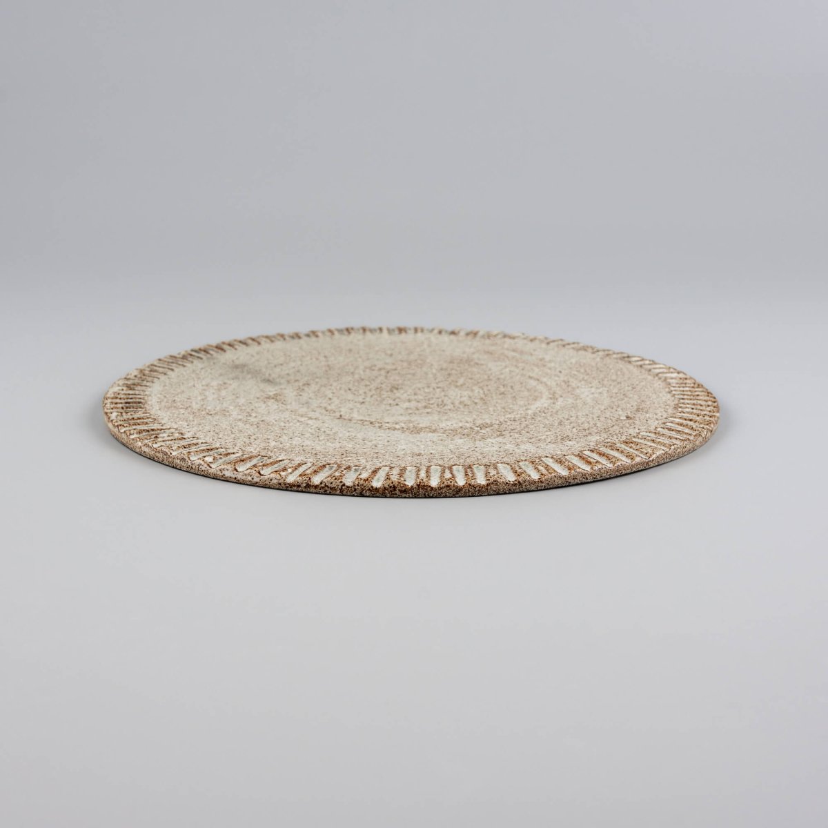 Flat handcrafted ceramic plate ideal for fine dining and culinary presentation.