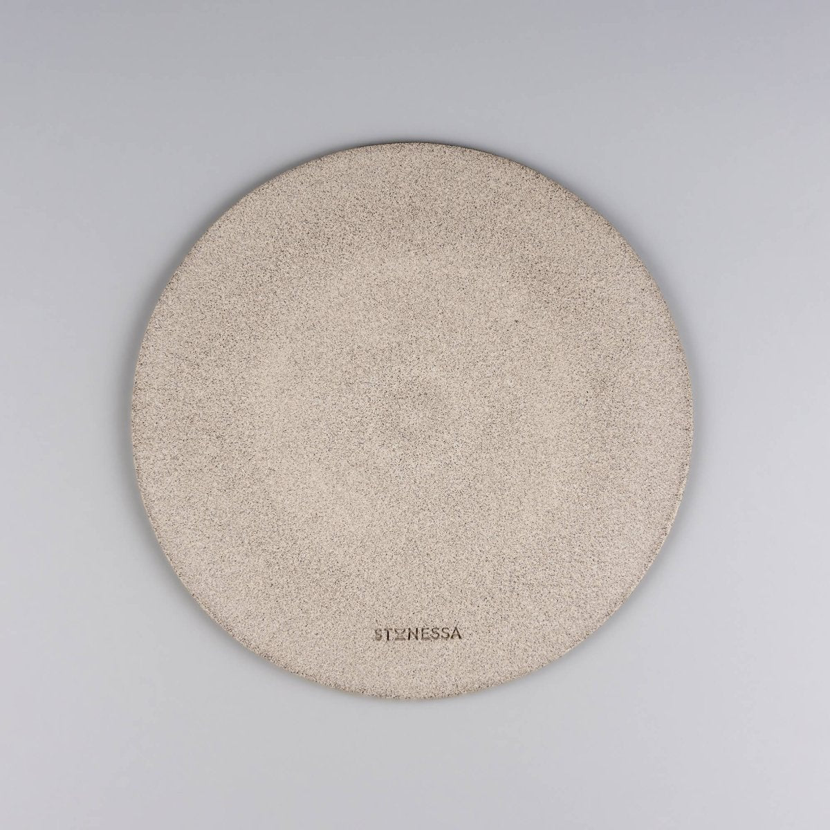 Backside of textured ceramic plate with raw clay base and carved finish.