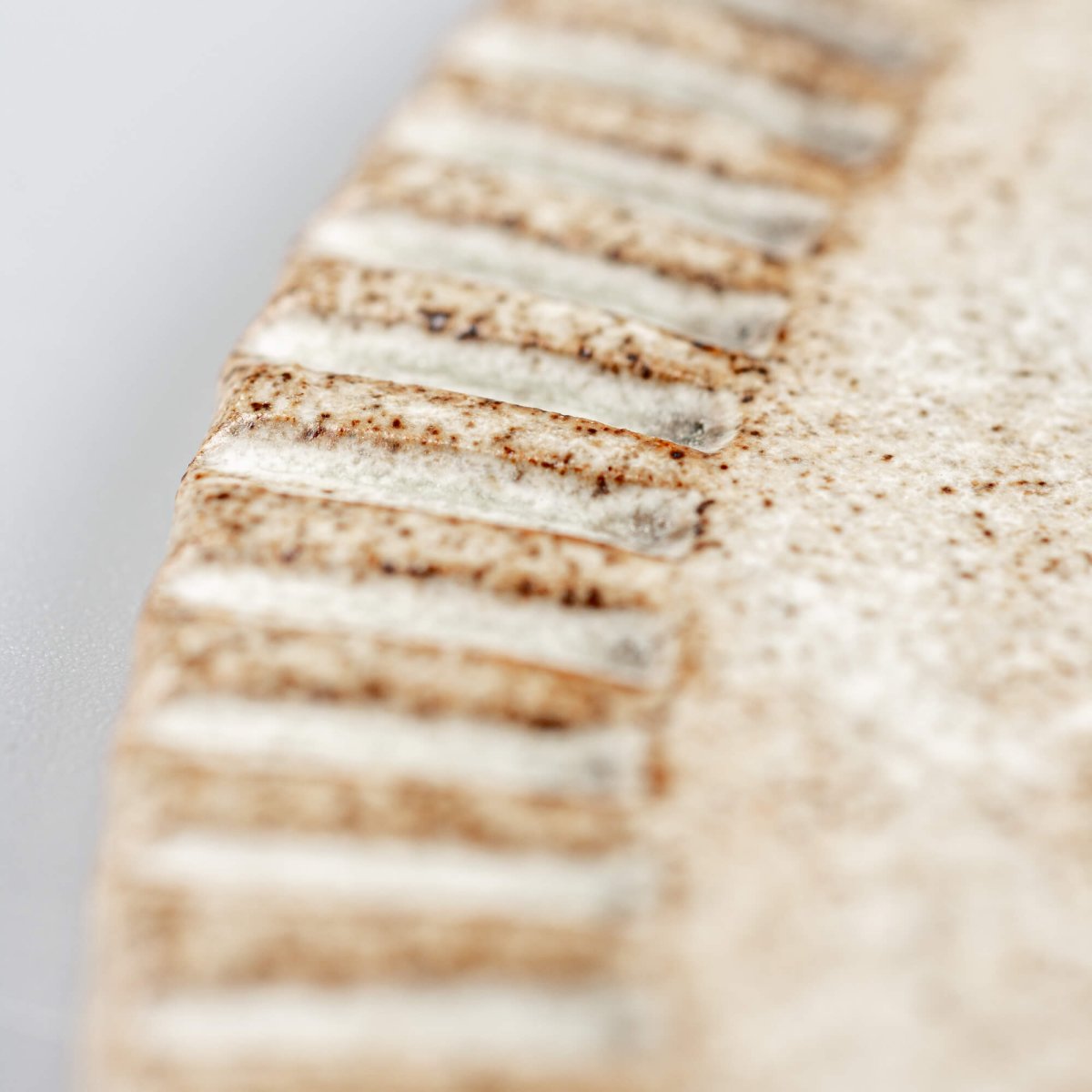 Detail of hand-carved edge on unique ceramic plate for collectors and stylists.