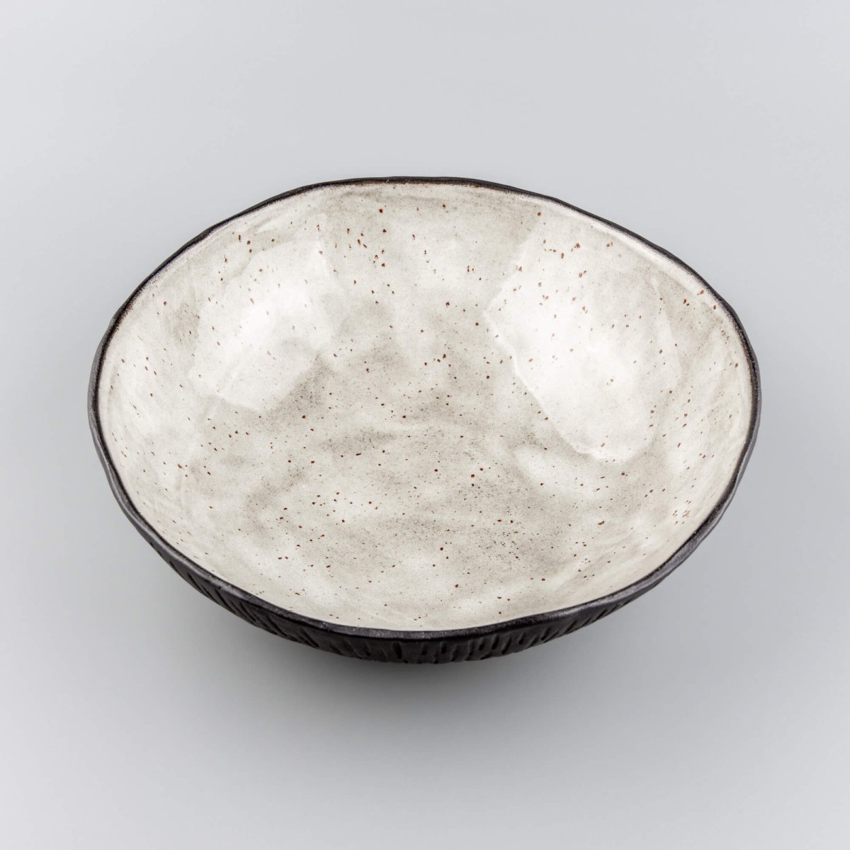 Angled view of artisan-made ceramic bowl highlighting its organic shape and dual-tone design.