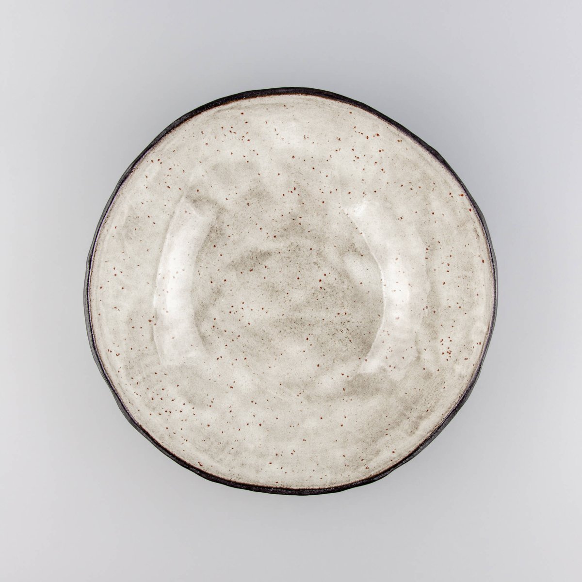 Top-down view of handcrafted ceramic bowl showing beige glazed interior with natural irregular rim.