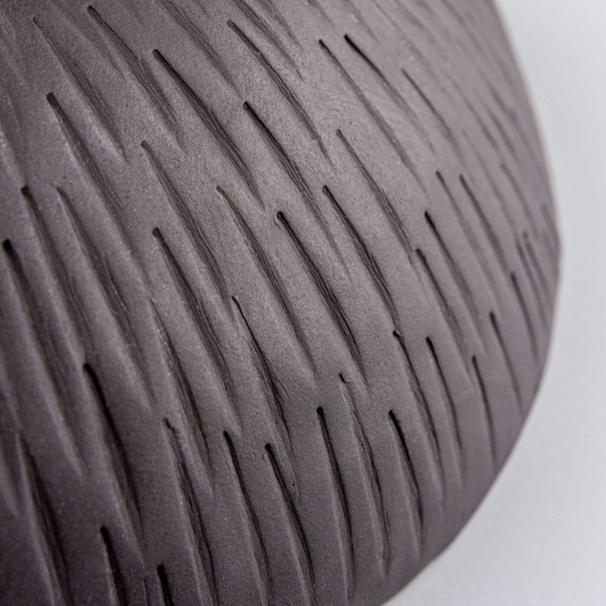 Detail of hand-carved vertical lines on black stoneware exterior of artisan serving bowl.