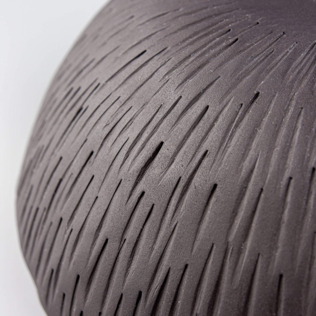 Macro close-up of ceramic texture showing natural ridges and hand-carved pottery pattern.