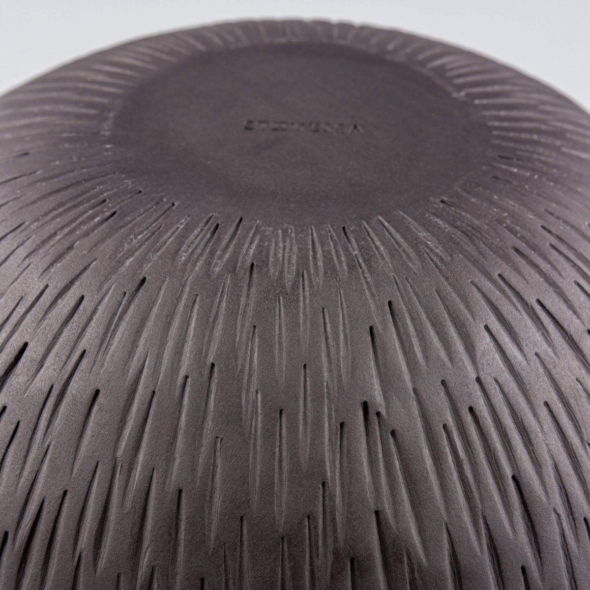 Detailed texture shot of black clay surface showing deep pottery carving and tactile finish.