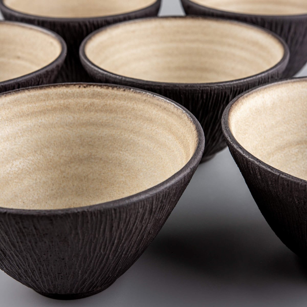 Group of dark artisan bowls with beige interiors, ideal for interior design and culinary service.
