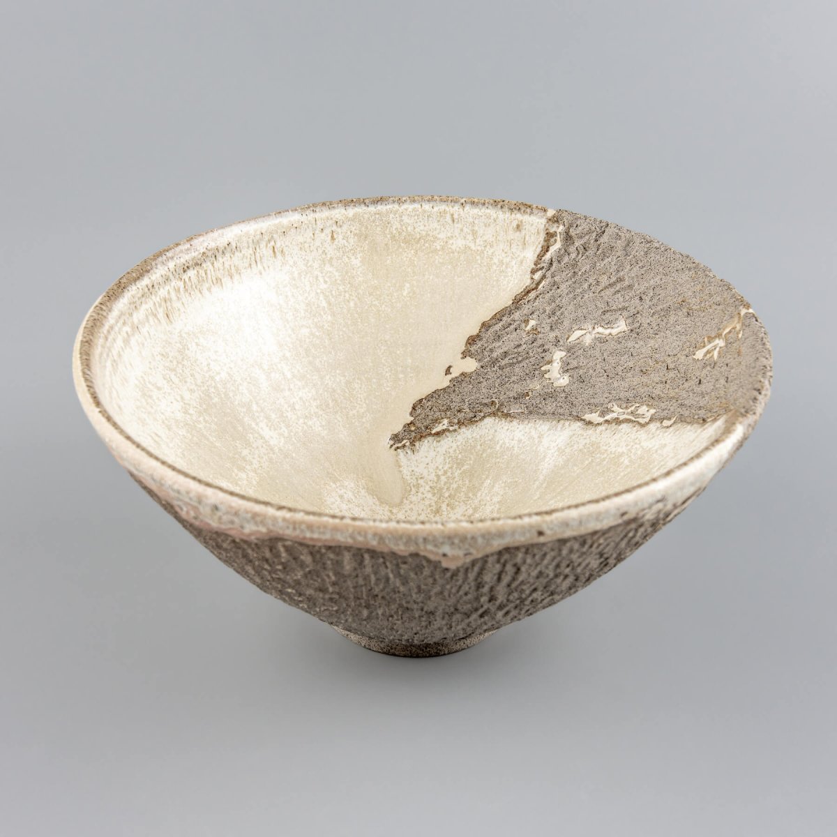 Side profile of large stoneware centerpiece bowl with beveled edges and rustic modern shape.