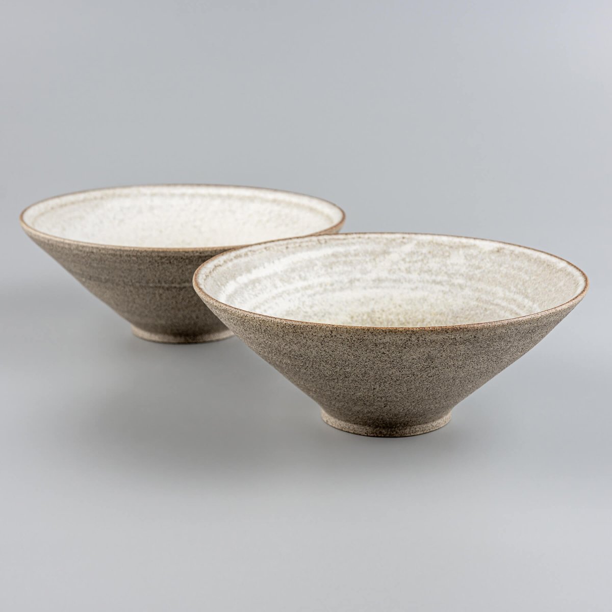 Pair of handmade stoneware bowls placed side-by-side to show natural ceramic variation.
