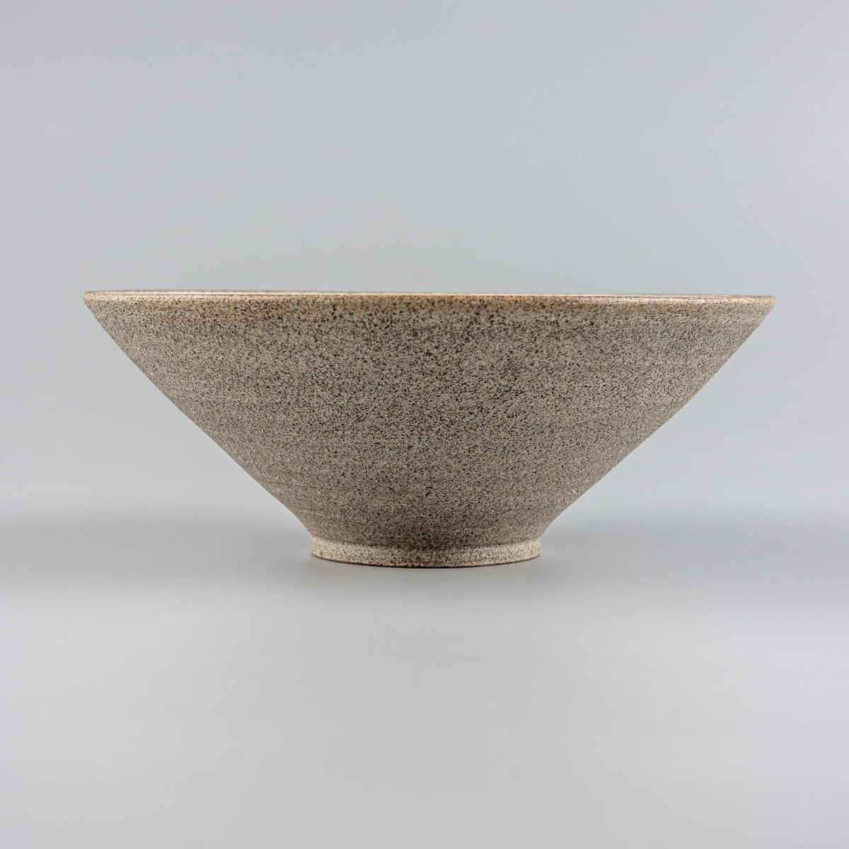 Back view of handcrafted ceramic bowl revealing natural unglazed base and curved form.