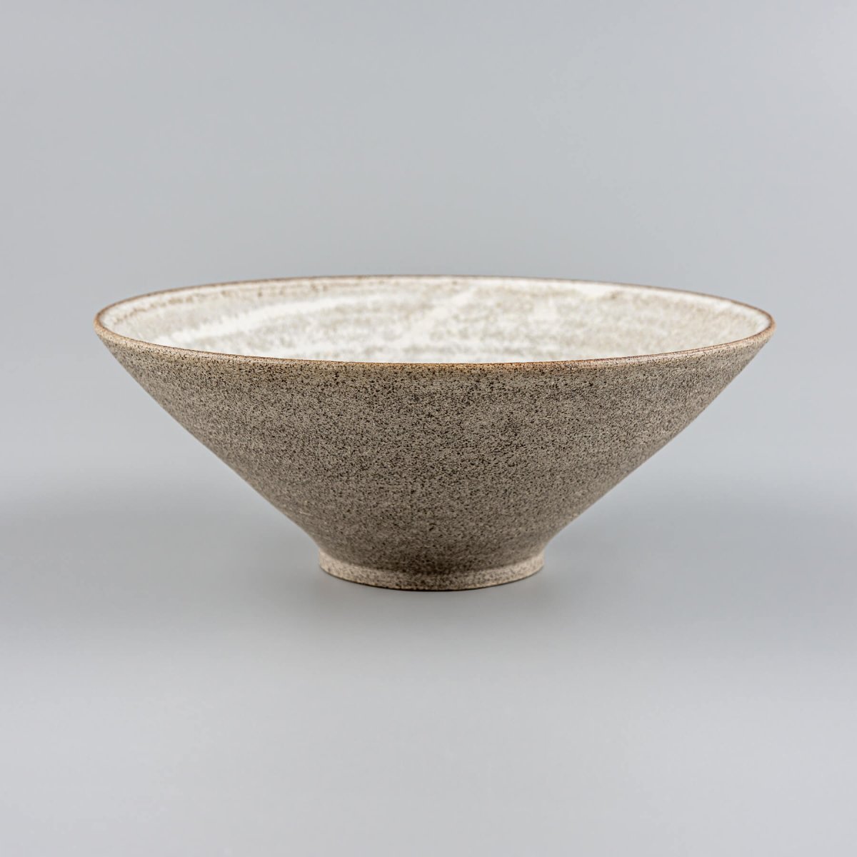 Side view of a handmade ceramic bowl with tall V-shaped profile and glazed stoneware surface.