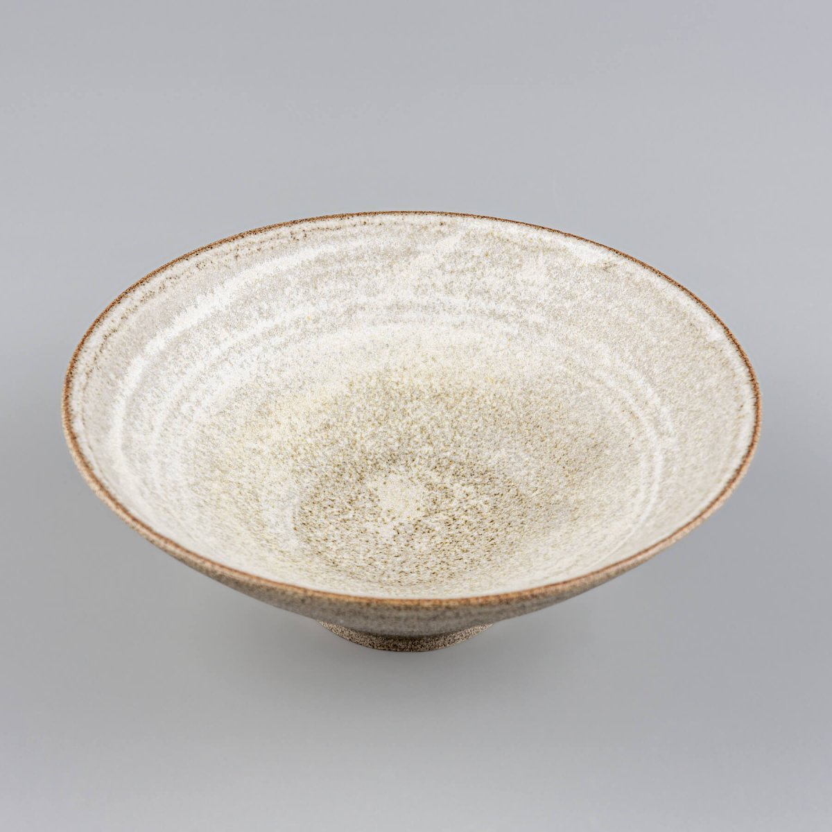Angled front view of handmade pottery bowl with natural stoneware texture and high walls.