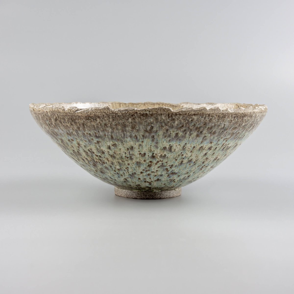 Profile view of artisan handmade ceramic bowl with curved edge and minimalist base.