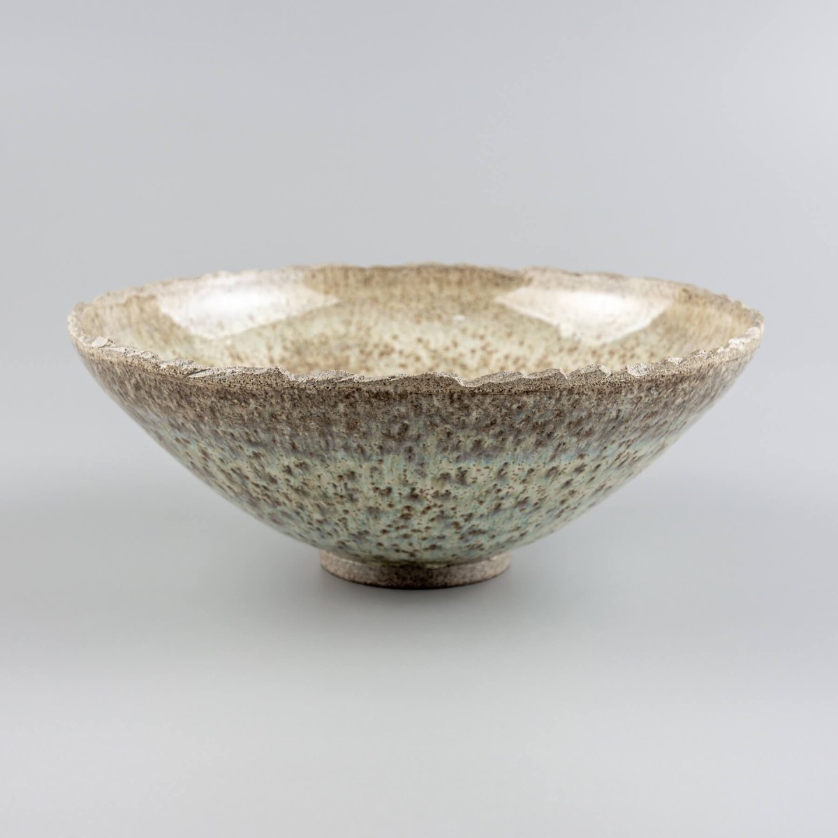 Handmade ceramic bowl with rustic stoneware texture and modern flared shape, perfect for serving or decor.