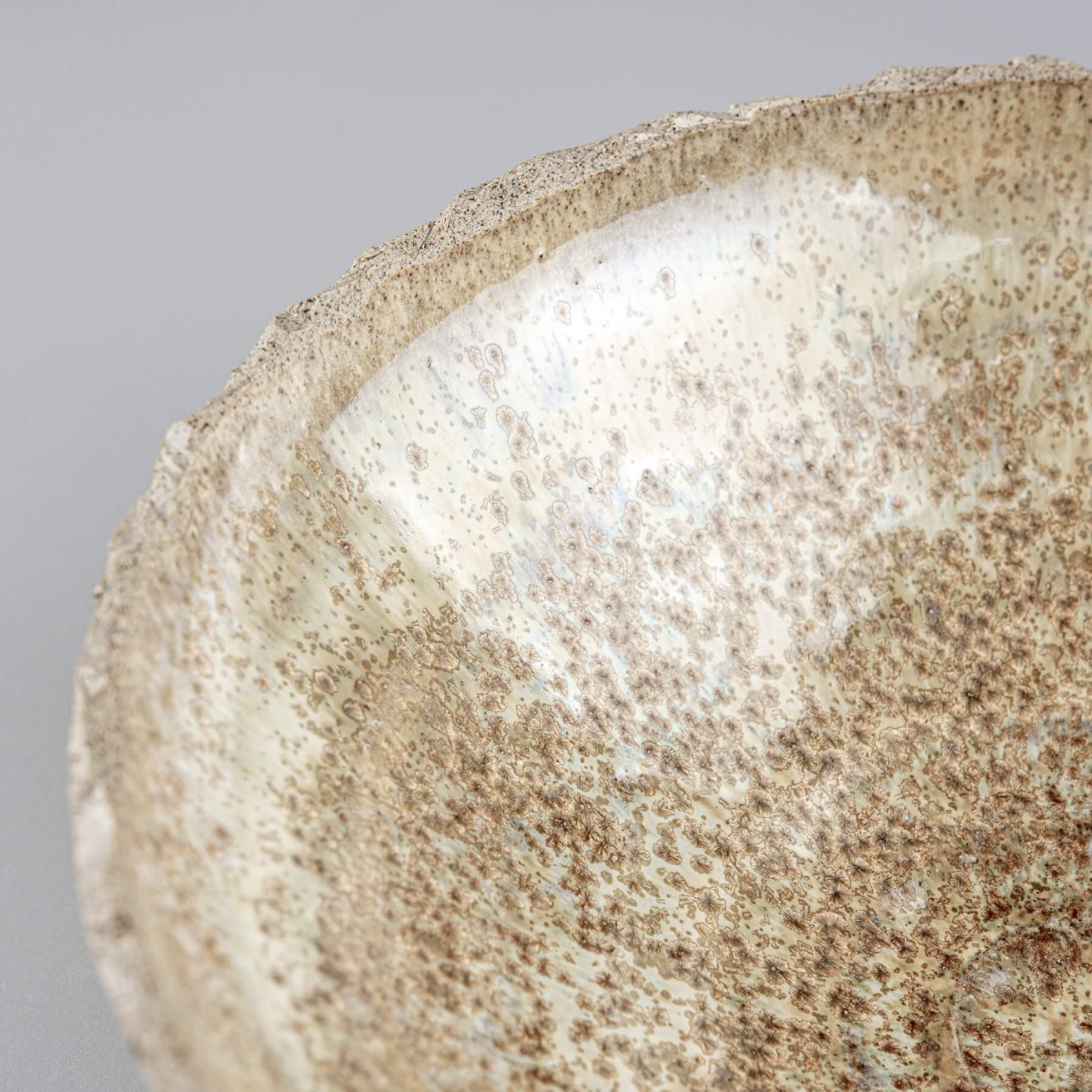 Detail of handmade stoneware bowl showing unique glaze and natural textured clay surface.