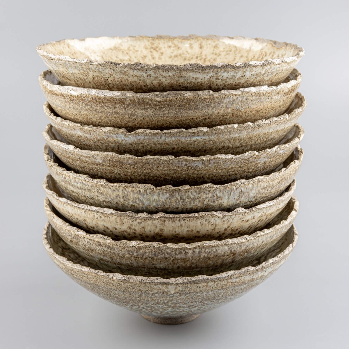 Group of handcrafted ceramic bowls showing unique glaze variations and rustic charm.