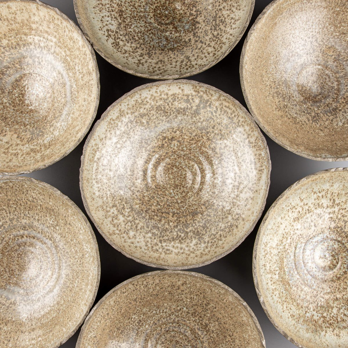 Close-up of handmade pottery bowls highlighting smooth glaze and natural stoneware texture.