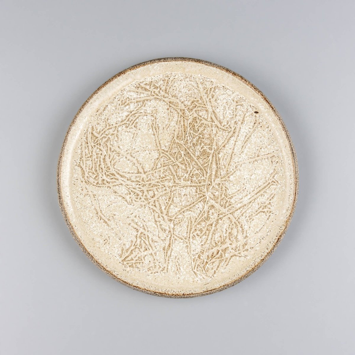 Handmade stoneware plate with embossed surface, ideal for serving desserts in fine dining settings.
