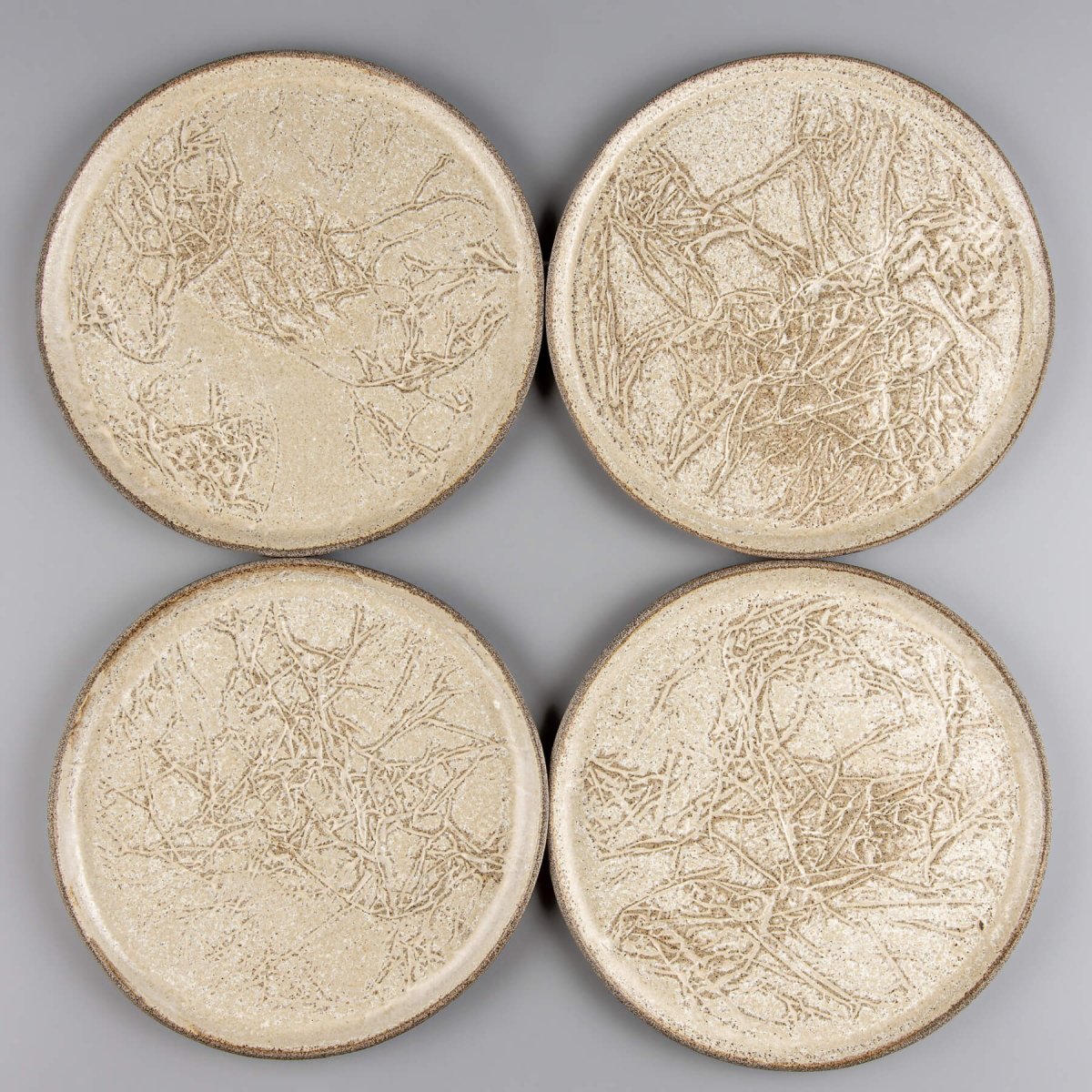 Four artisanal stoneware plates arranged for fine dining or home decor.