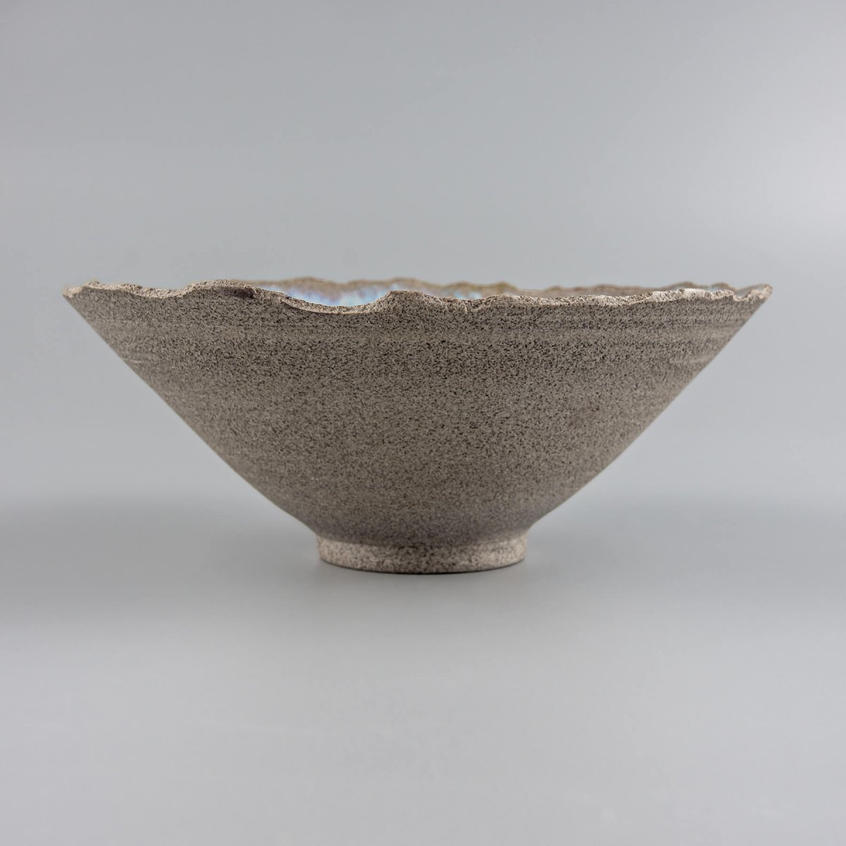 Profile view of artisan bowl emphasizing tall V-shaped form and footed base.