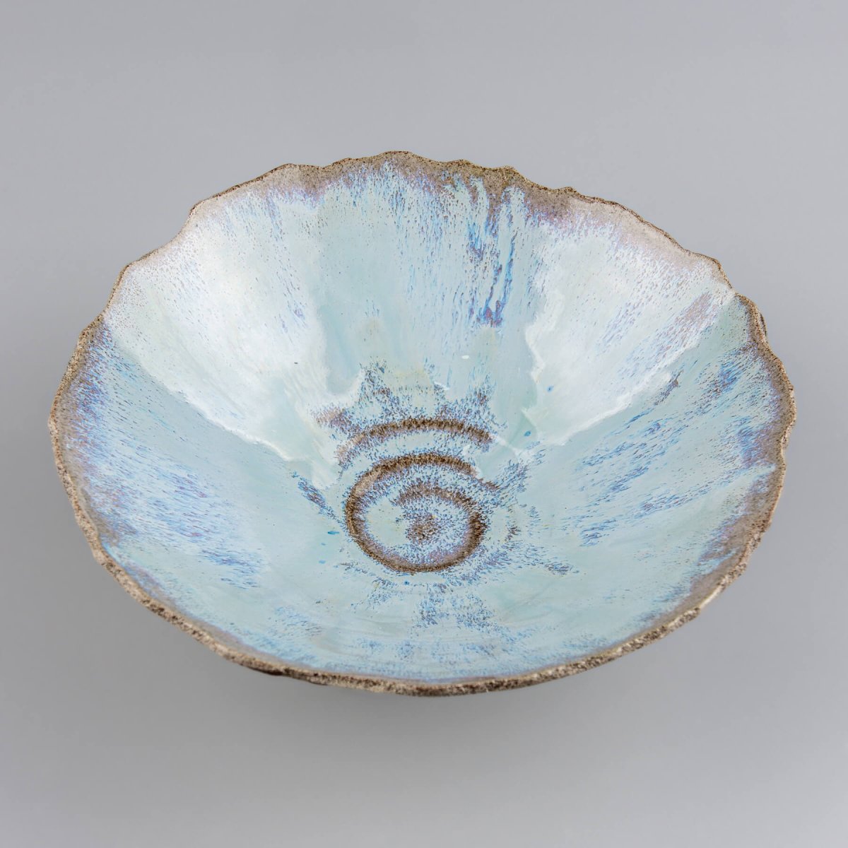 Side view of rustic ceramic bowl with textured unglazed exterior and stable base.