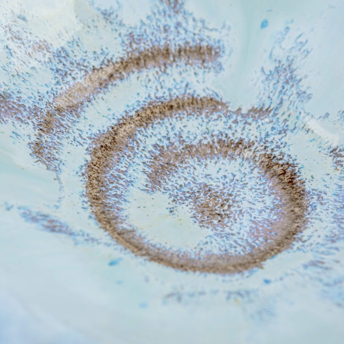 Detailed shot of spiral pattern at the center of blue-glazed ceramic bowl.