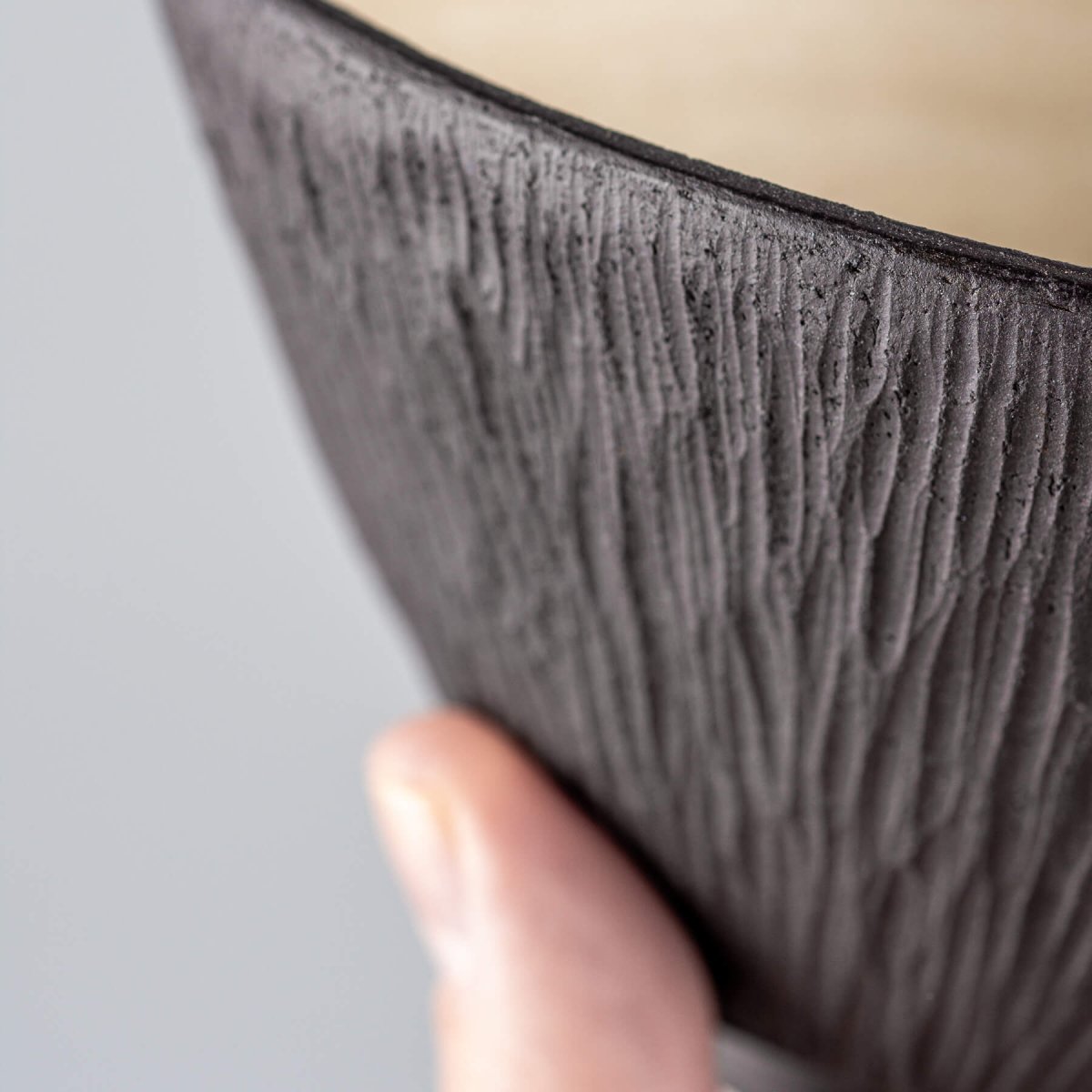 Detail of textured black clay carving on the bowl’s exterior, showcasing artisanal craftsmanship.