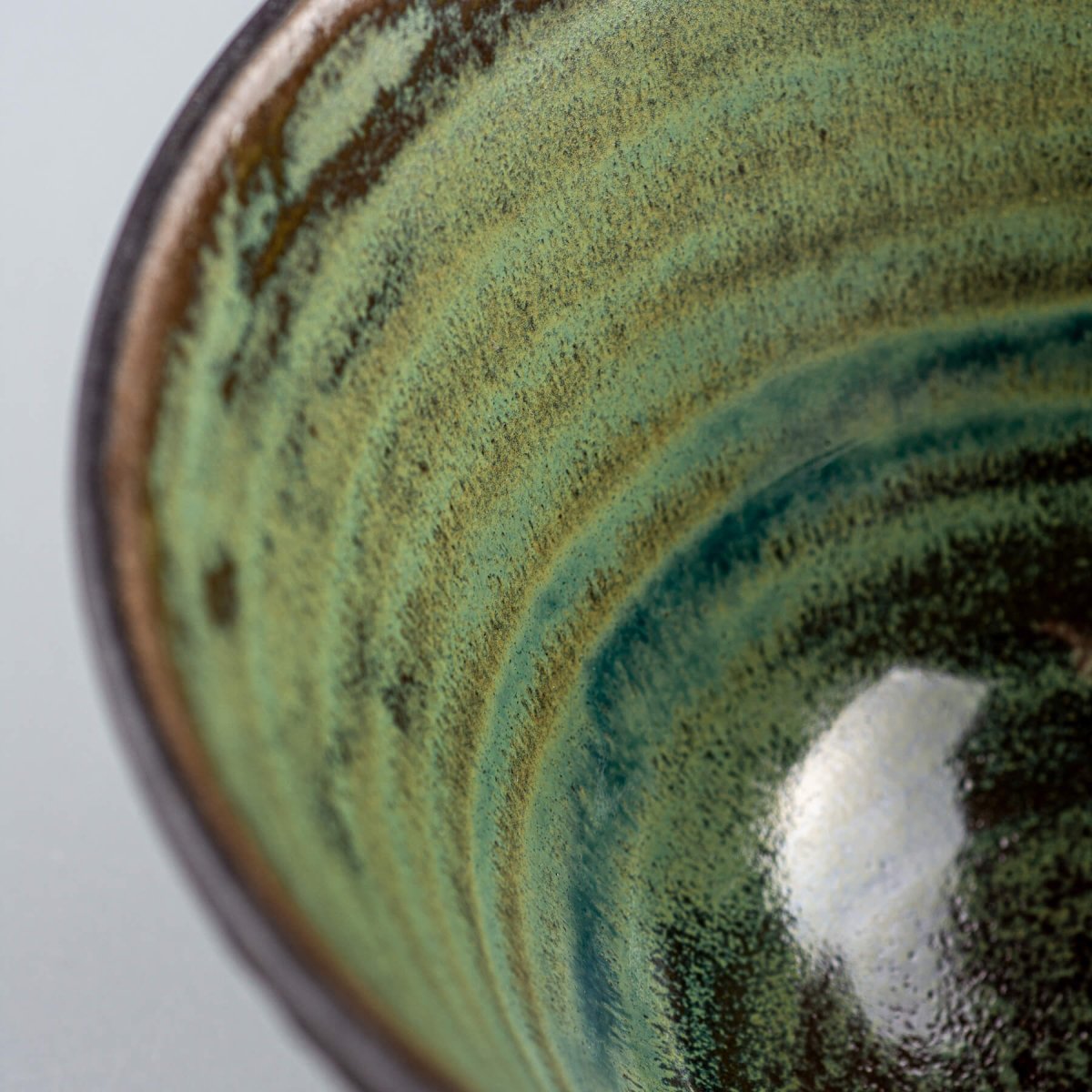 Close-up of green glazed ceramic surface with artistic pottery details.