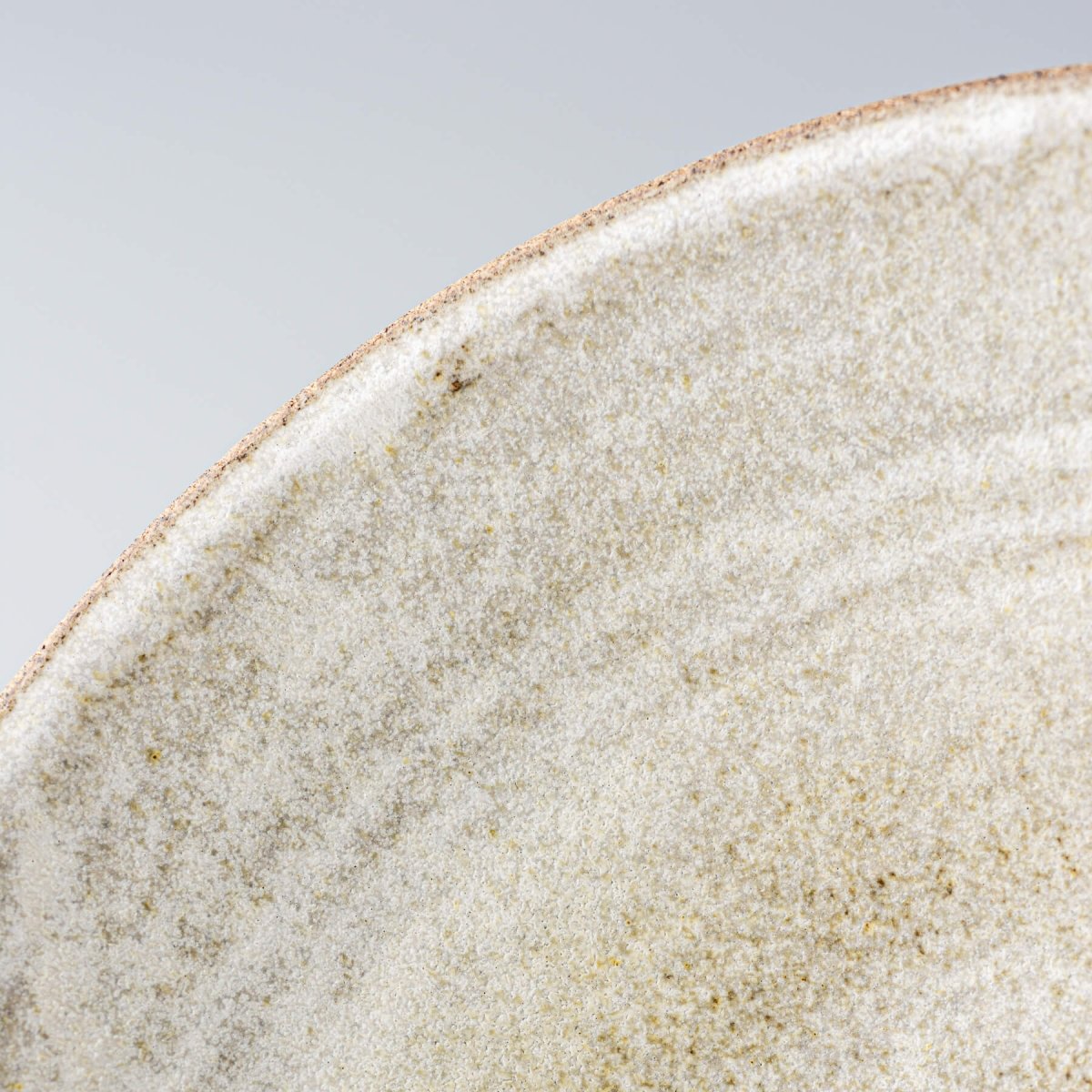 Macro shot of glazed rim and interior texture of artisan-crafted ceramic serving bowl.