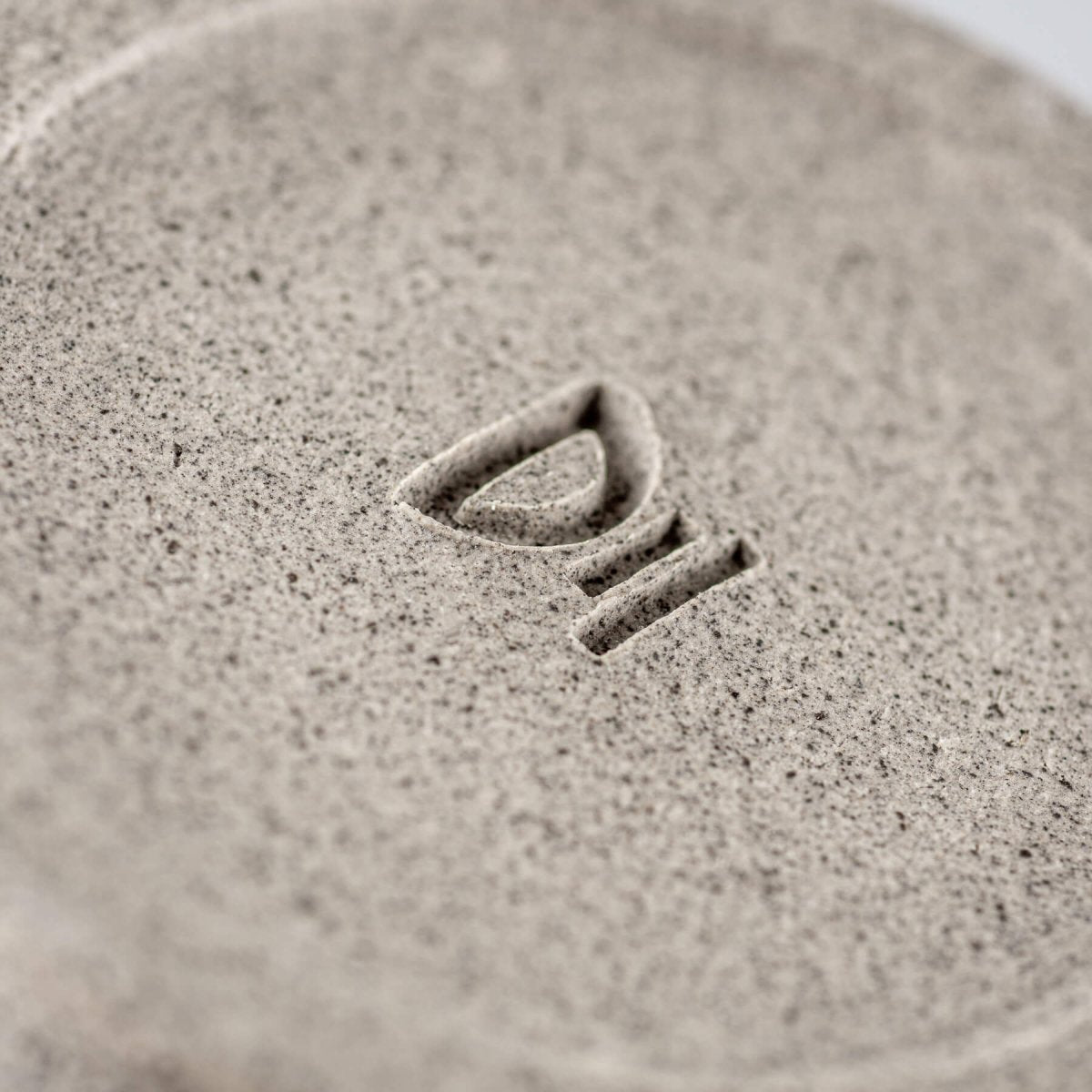 Bottom stamp detail showing artisan signature on handmade stoneware ceramic bowl.