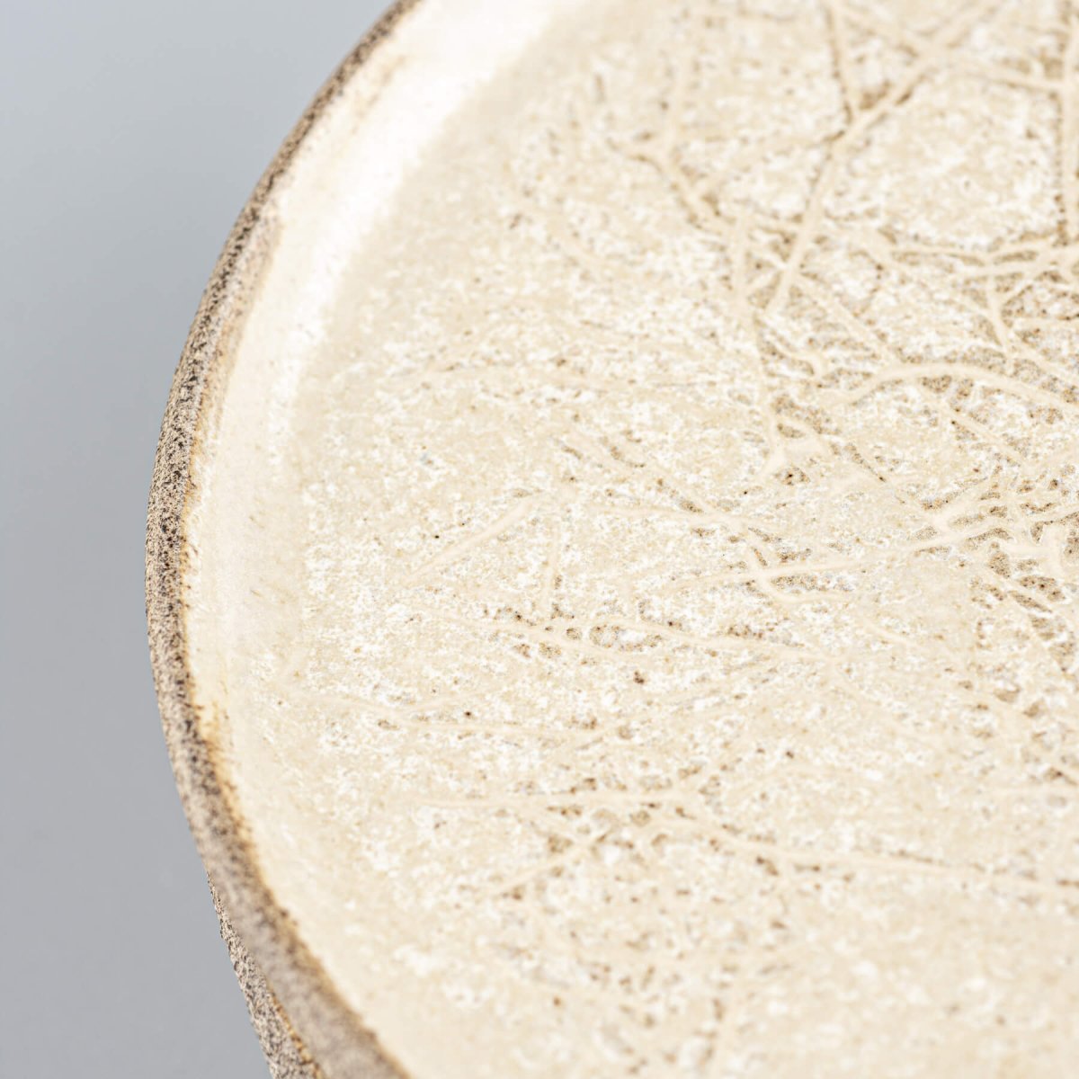 Flat stoneware plate with natural texture, suited for cheese or appetizers.