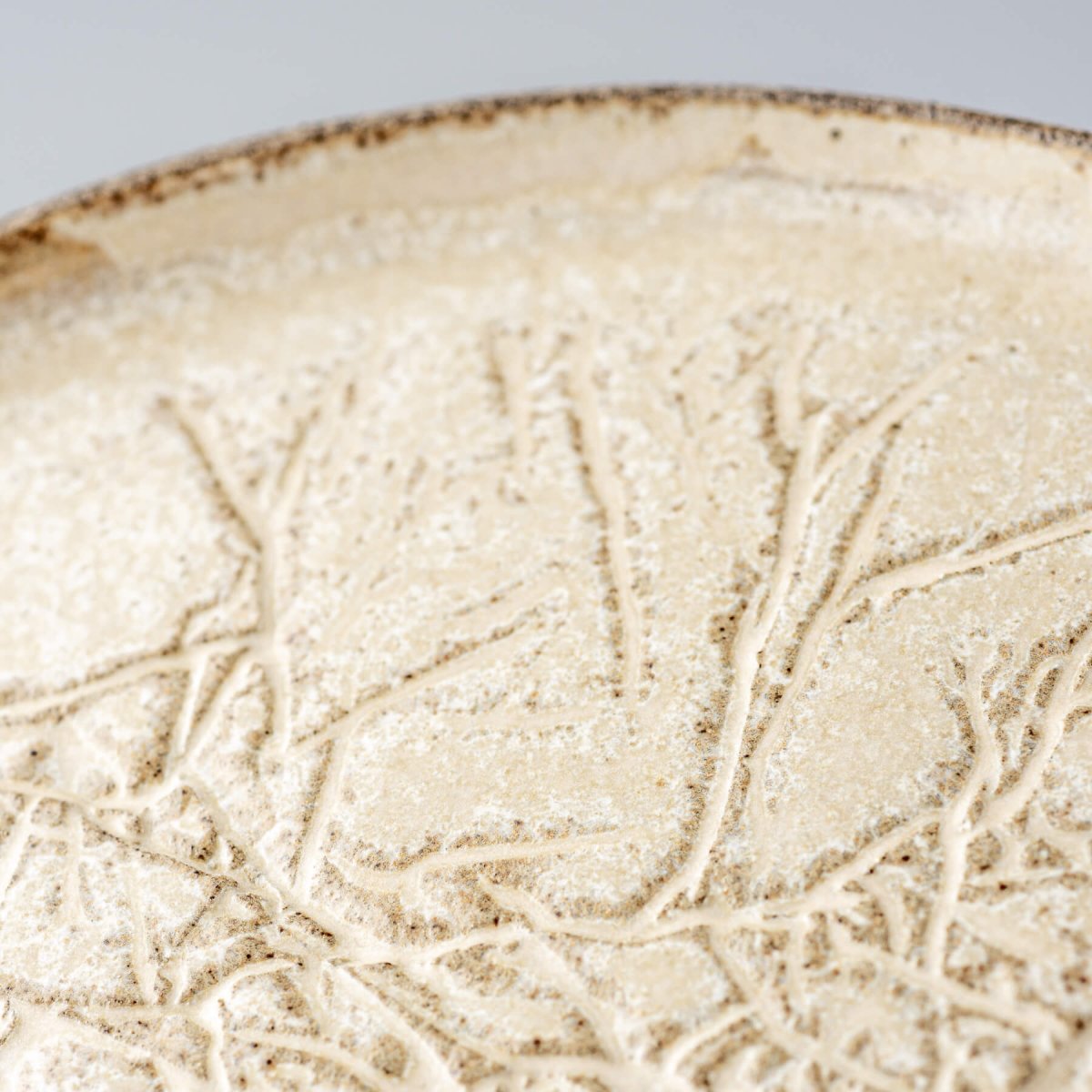 Close-up of artisanal surface pattern on decorative ceramic dinner plate.