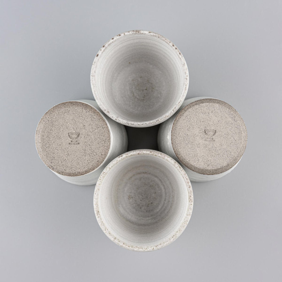 Four handmade stoneware mugs arranged for modern kitchen and boutique restaurant use.