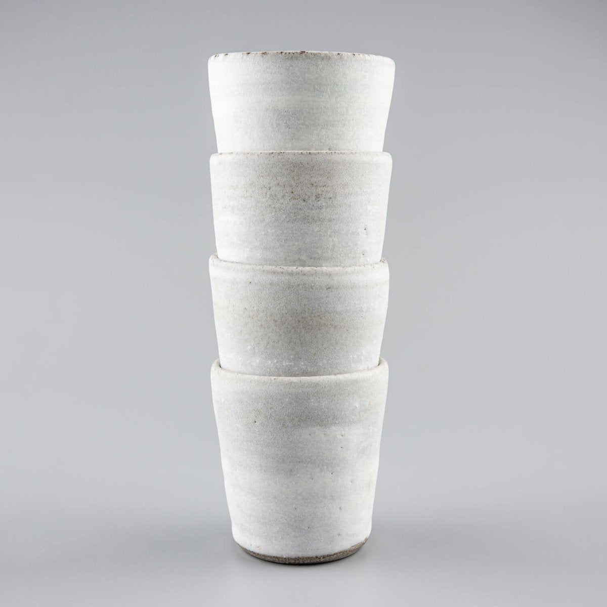 Vertical arrangement of handmade ceramic mugs with timeless design for tableware collections.