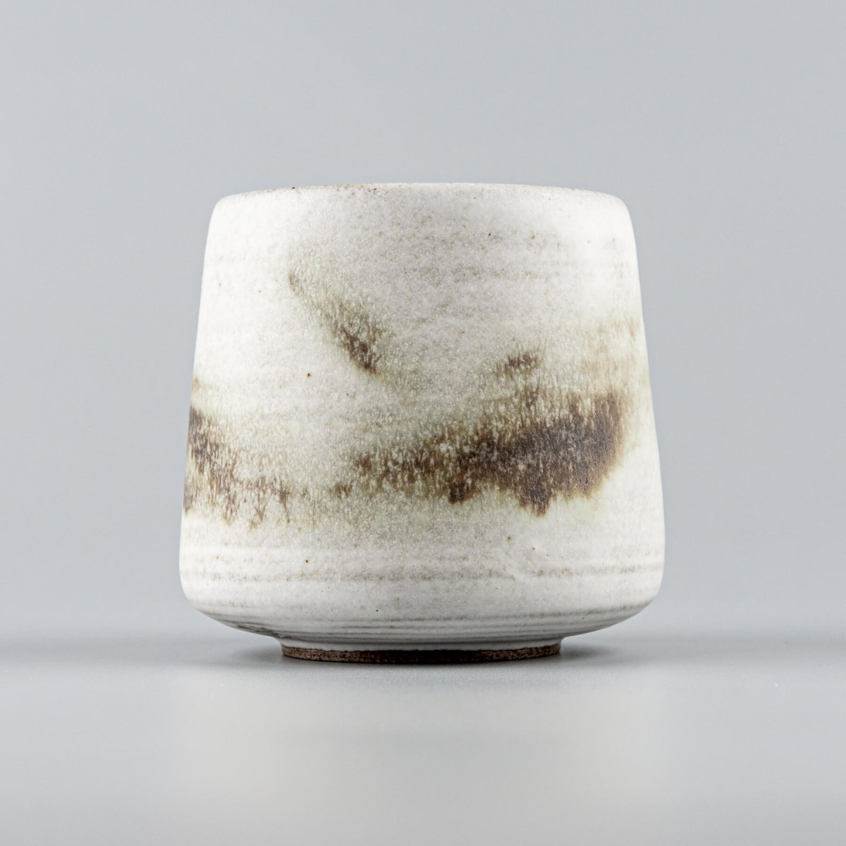 Handcrafted ceramic espresso cup with white matte glaze and copper oxide accents for fine dining presentation.