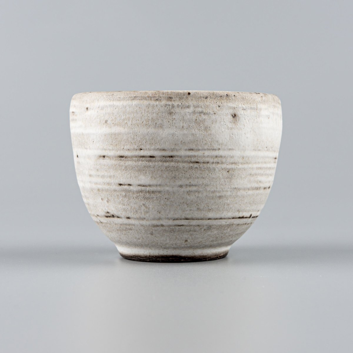 Handmade coffee mugs with white matte glaze, crafted from dark stoneware clay for unique artisanal tableware.