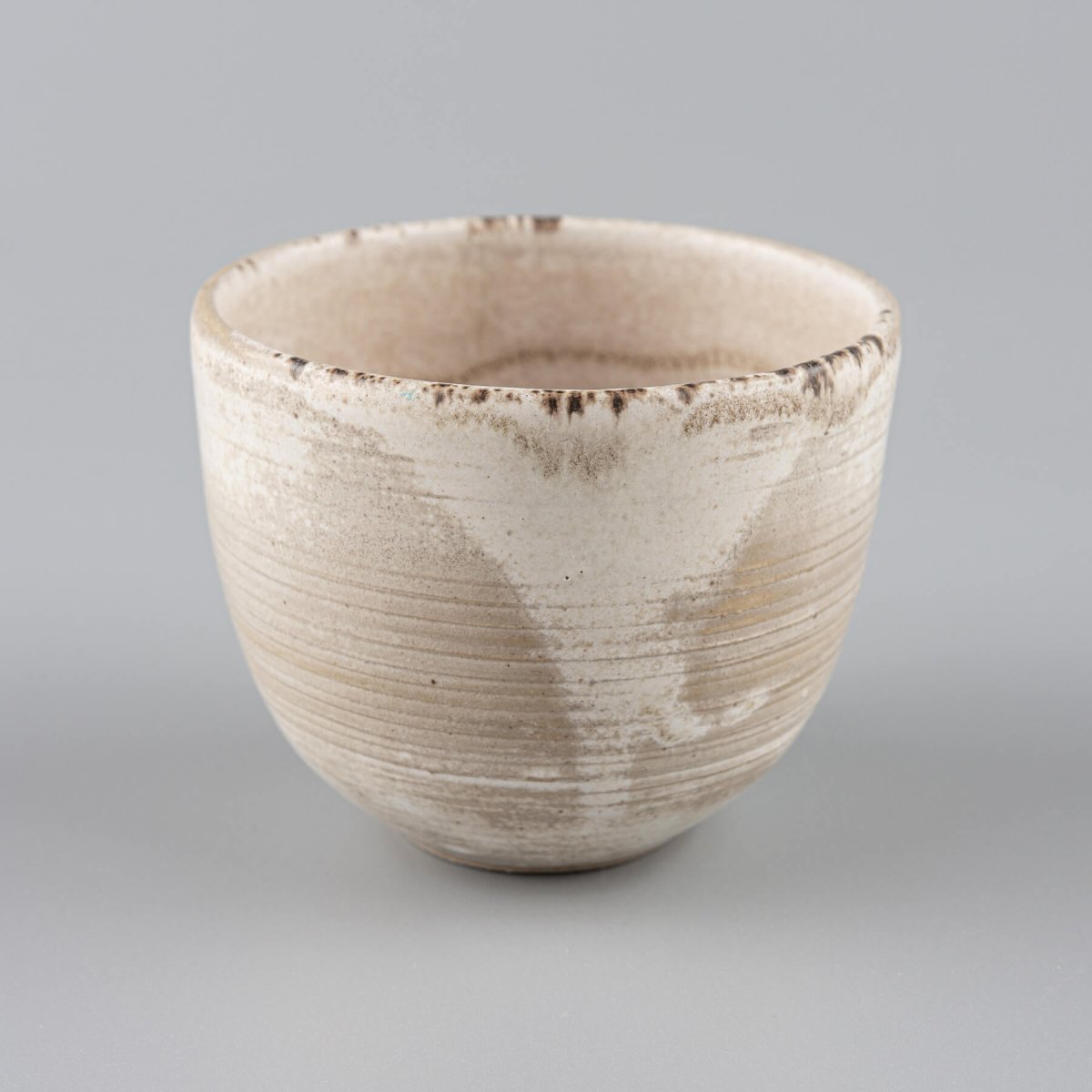 Artisan stoneware coffee cups with engraved lines and rustic matte finish for modern culinary presentation.