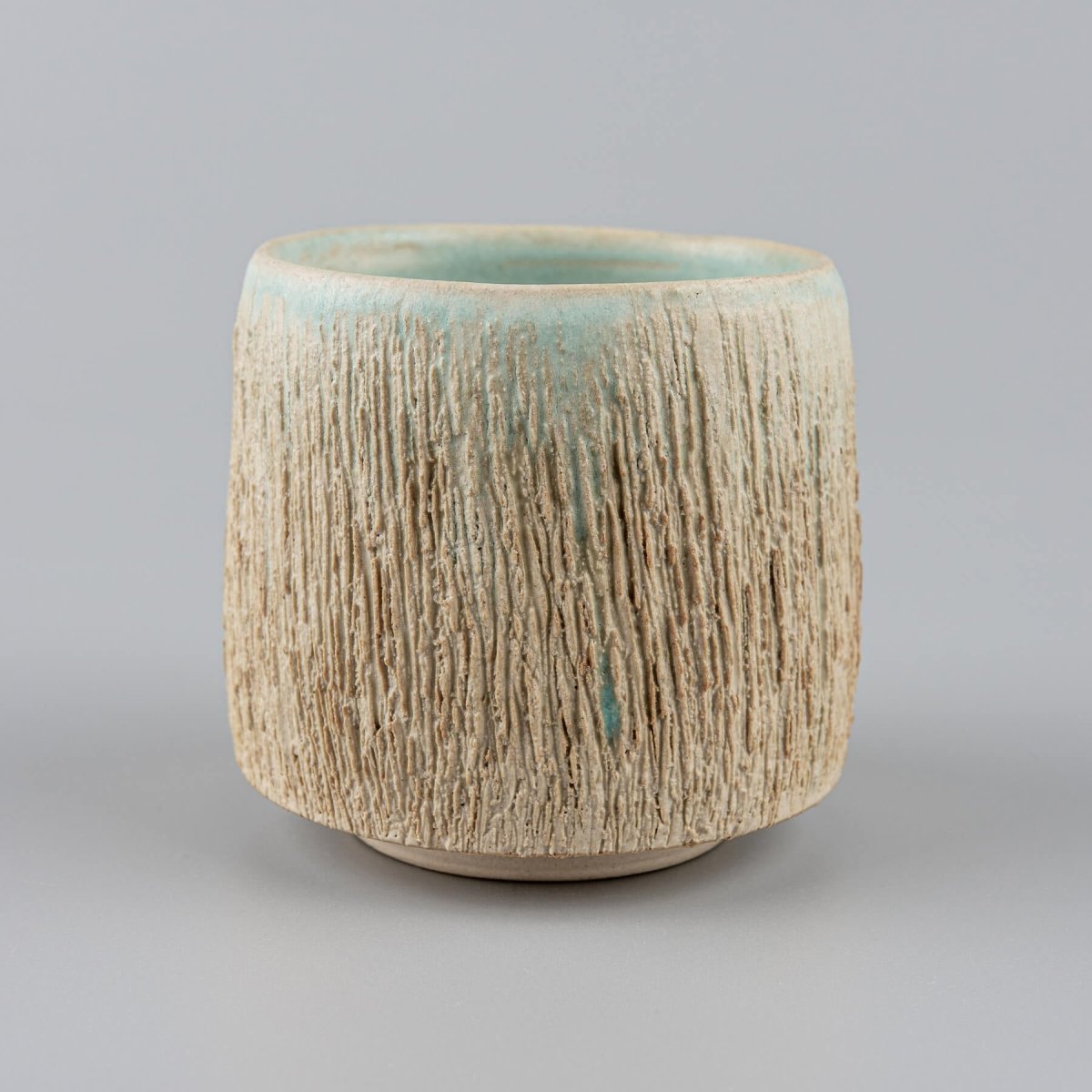 Handcrafted ceramic mugs with rustic carved texture, ideal for boutique hotels and restaurants.