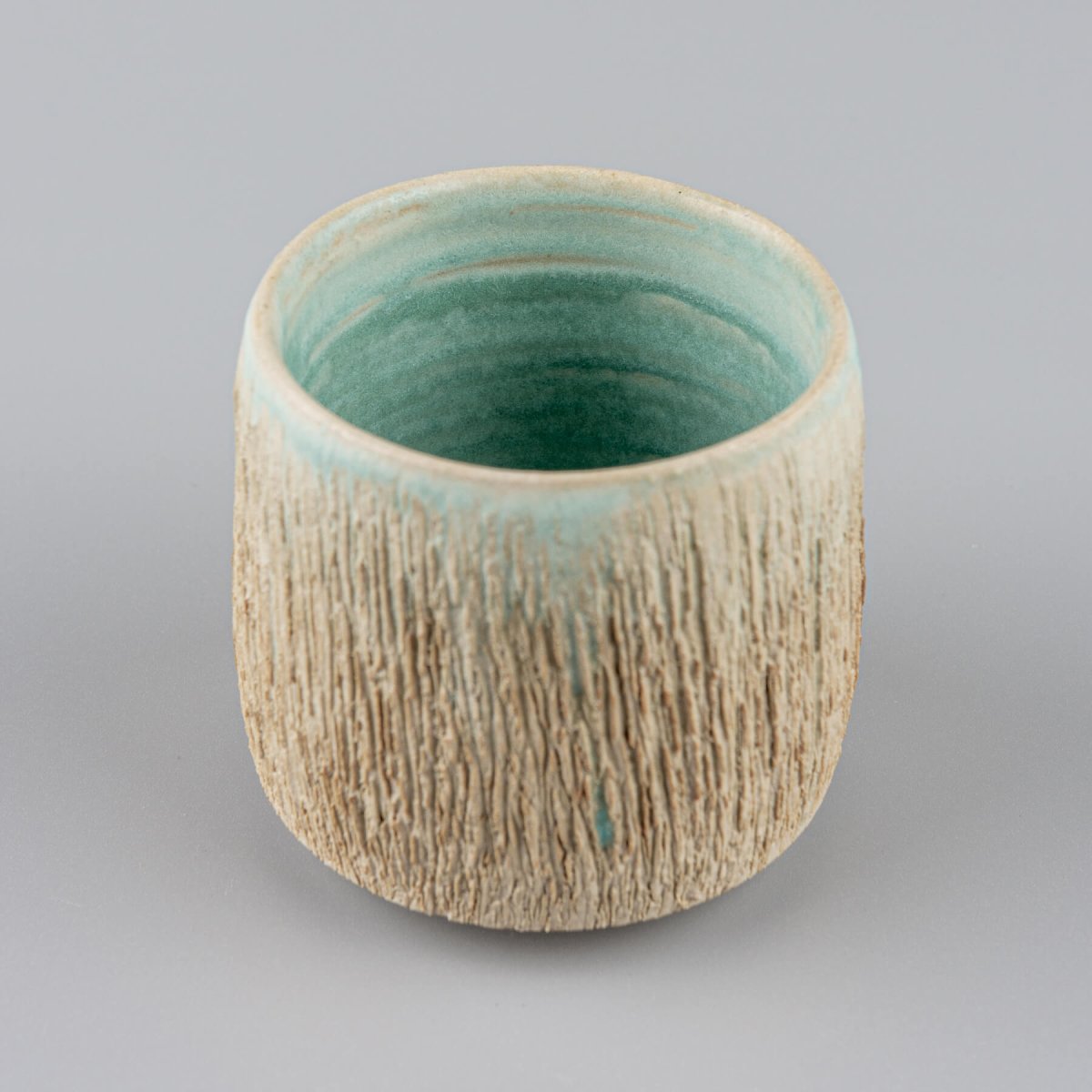 Artisanal textured ceramic mug with aqua interior, collectible pottery for private collectors.