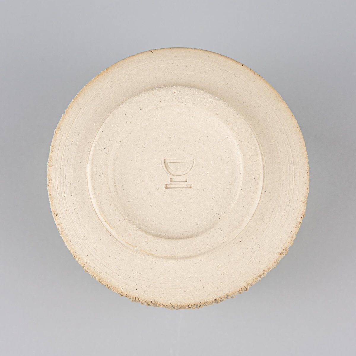 Bottom of handcrafted stoneware mug with natural clay finish, collectible handmade decor.
