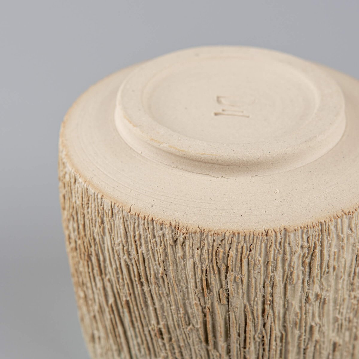 Close-up of rustic carved texture on pottery mug, artisanal ceramic tableware for restaurants.